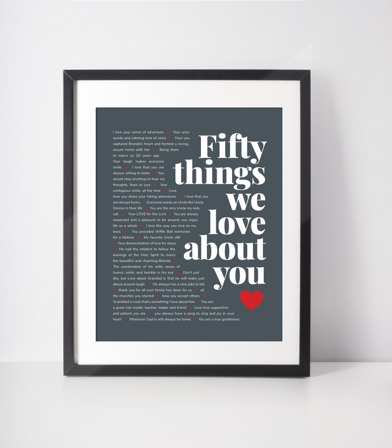 May include: A dark grey framed print with a red heart and white text that reads "Fifty things we love about you". The text is a list of reasons why someone is loved.