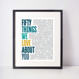 May include: Framed art print with the words "FIFTY THINGS WE LOVE ABOUT YOU" in teal, yellow, and white. The print is a list of loving sentiments. The frame is black.