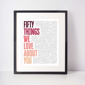 May include: Framed print with the text "FIFTY THINGS WE LOVE ABOUT YOU" in a colorful, layered design. The text is surrounded by a black frame and set against a white background. The print lists various reasons why someone is loved.