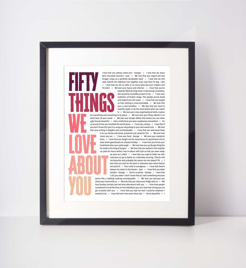 May include: Framed print with the text "FIFTY THINGS WE LOVE ABOUT YOU" in a colorful, layered design. The text is surrounded by a black frame and set against a white background. The print lists various reasons why someone is loved.