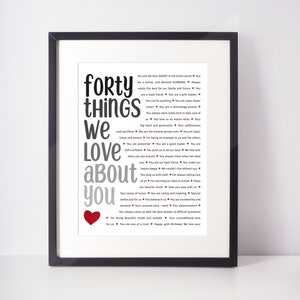 Peut inclure: Une impression encadrée avec un cadre noir et un fond blanc. L'impression présente une liste de 40 choses que la personne aime chez quelqu'un, avec les mots "forty things we love about you" en grandes lettres grises. Le texte est entouré de petits cœurs rouges.