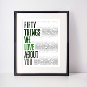 May include: A framed print with the words "FIFTY THINGS WE LOVE ABOUT YOU" in large, green and gray letters. The text is surrounded by a list of phrases in a smaller font.