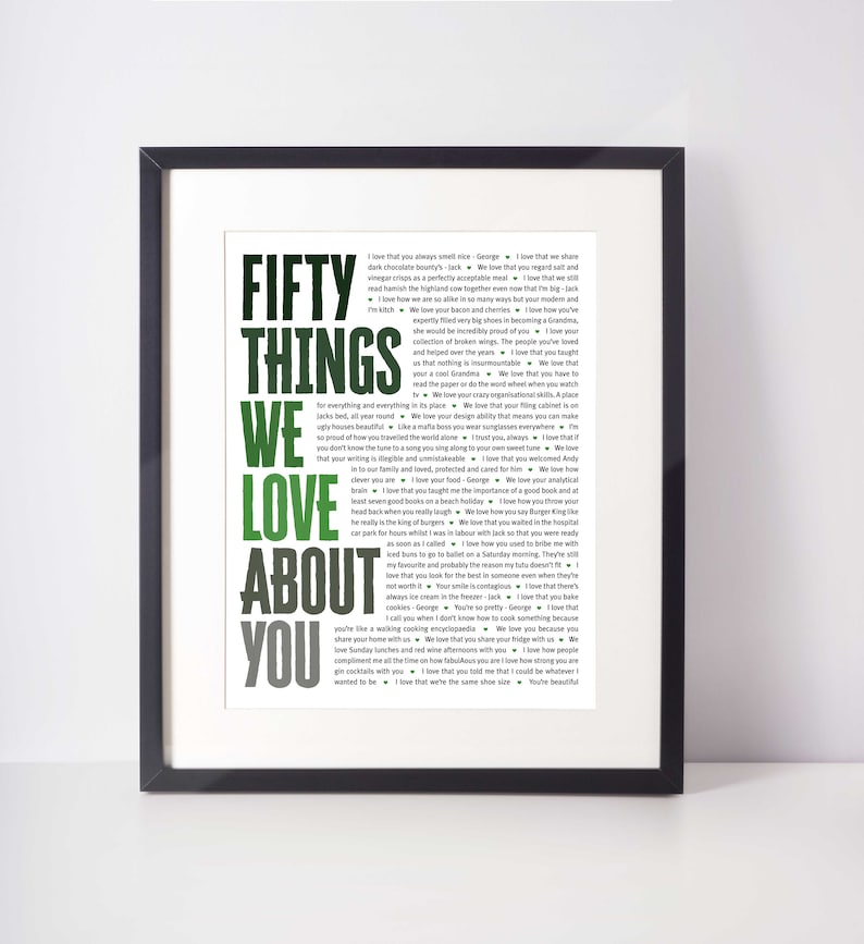May include: A framed print with the words "FIFTY THINGS WE LOVE ABOUT YOU" in large, green and gray letters. The text is surrounded by a list of phrases in a smaller font.
