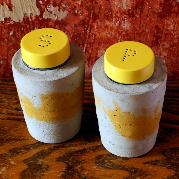 Pair of ridged grey and yellow concrete cast salt and pepper shakers with yellow lids