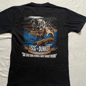 May include: Black t-shirt featuring a graphic of a bearded figure with a trident, lightning, and a boat. Text on the shirt reads "USCG DUNKER" and "SO THE SEA SHALL NOT HAVE THEM."