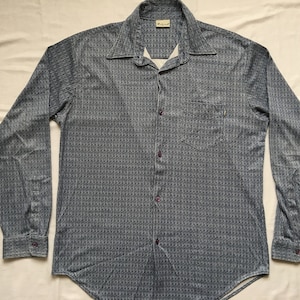 May include: A long-sleeved button-down shirt with a blue and white geometric pattern. The shirt has a pointed collar and a single chest pocket.