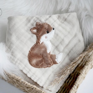 May include: A beige muslin baby burp cloth with an embroidered brown fox design.