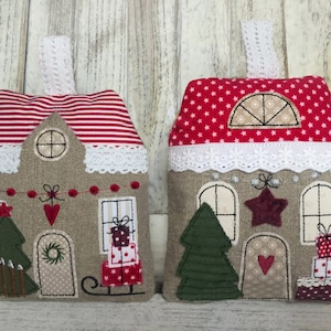 Könnte beinhalten: Zwei handgemachte Weihnachts-Türstopper in Hausform mit rot-weiß gestreiften und rot gepunkteten Dächern, einem grünen Baum und einem roten Herzen auf der Vorderseite.