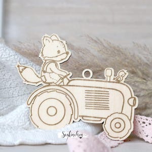 Könnte beinhalten: Ein Holzausschnitt eines Fuchses, der einen Traktor mit einem Vogel auf der Ladefläche fährt. Der Ausschnitt ist hellbraun und hat einen rustikalen Look.