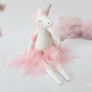 Op de afbeelding: Een witte eenhoornpop met een roze tule tutu en een zilveren sterretjesstaf. De pop heeft gesloten ogen en een glinsterend hoorn.