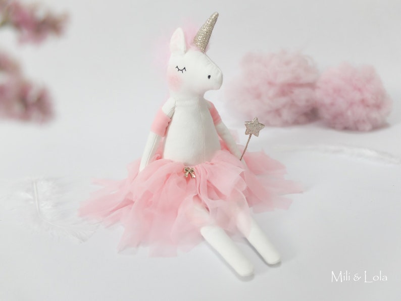 Op de afbeelding: Een witte eenhoornpop met een roze tule tutu en een zilveren sterretjesstaf. De pop heeft gesloten ogen en een glinsterend hoorn.