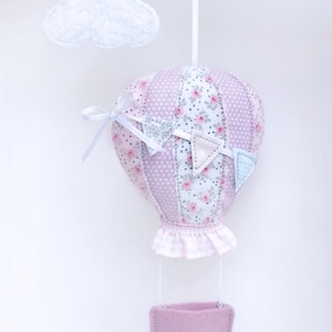 May include: A pink and white hot air balloon with a floral pattern and a pink basket hanging from it. The balloon is attached to a white string and a white cloud is hanging above it. The text "STICKHERZ" is visible in the top right corner of the image.