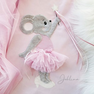 Puede incluir: Un ratón rosa y gris con un tutú rosa y sosteniendo una varita rosa y blanca. El ratón está sobre un fondo rosa con el nombre "Johllina" escrito en cursiva.