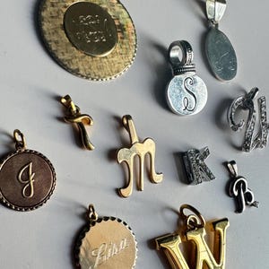 Dijes y colgantes vintage de plata con iniciales y nombres, tono plateado, plata de ley y acero inoxidable, varios metales.