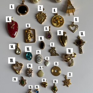 May include: A collection of 32 gold-tone pendants with various designs, including hearts, animals, religious symbols, and abstract shapes. Some pendants feature gemstones, pearls, and other decorative elements.