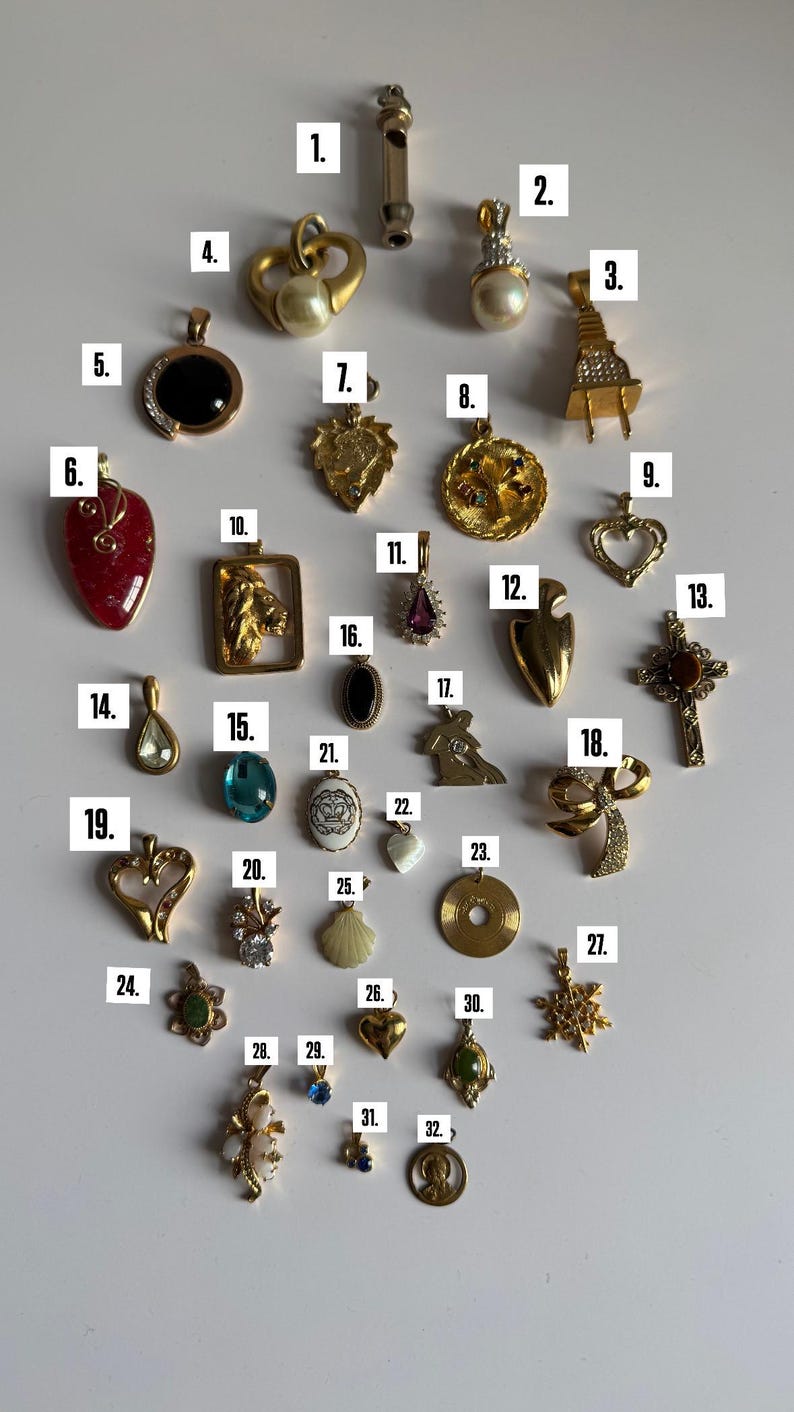 May include: A collection of 32 gold-tone pendants with various designs, including hearts, animals, religious symbols, and abstract shapes. Some pendants feature gemstones, pearls, and other decorative elements.