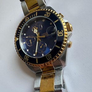 May include: A two-tone gold and silver Citizen Eco-Drive chronograph wristwatch with a black face and a rotating bezel.