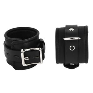 May include: Two black leather wrist cuffs with silver-colored buckles and hardware. The cuffs are thick and padded, with a strap and buckle closure. One cuff has a D-ring.