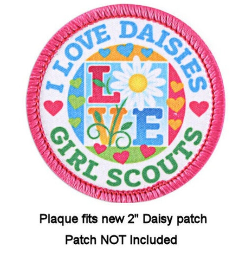 May include: A pink and white round patch with the text "I Love Daisies Girl Scouts" and a colorful flower design in the center. The patch is 2 inches in diameter.