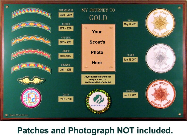 May include: Green wooden plaque with a gold frame, displaying a Girl Scout Journey to Gold award chart. The chart includes a space for a photo, a list of levels, and dates for each level. The plaque also features a Girl Scout logo and the words "My Journey to Gold".
