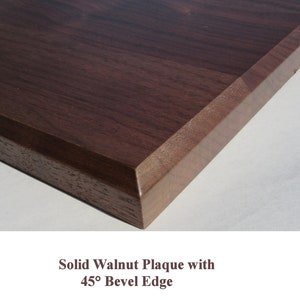 May include: Close-up of a solid walnut plaque with a 45-degree beveled edge. The wood has a rich brown color and a smooth finish.