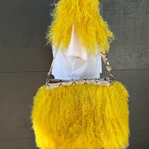 May include: A bright yellow curly fur handbag featuring a snakeskin-patterned leather strap and trim. The bag has a rectangular structure with a long, adjustable shoulder strap attached by metal hardware, showcasing a vibrant, textured appearance.