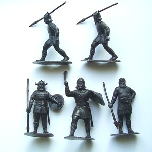 Puede incluir: Conjunto de seis guerreros vikingos de plástico negro. Las figuras sostienen lanzas, espadas y escudos.