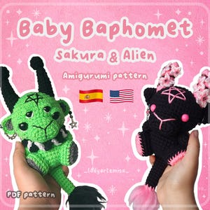 Puede incluir: Dos muñecos amigurumi de ganchillo, uno verde y otro negro, se muestran sobre un fondo rosa. El muñeco verde tiene un pentagrama en la cabeza y una cola negra. El muñeco negro tiene detalles rosas y cuernos florales. El texto dice "Baby Baphomet" y "Sakura & Alien".