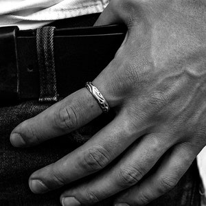 Puede incluir: Un anillo de plata con un dise&ntilde;o texturizado y org&aacute;nico. El anillo se lleva en el dedo de una persona que lleva pantalones vaqueros.