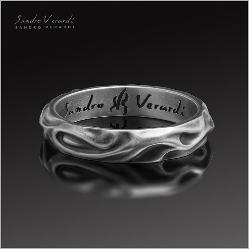 Puede incluir: Un anillo de plata con una superficie texturizada y ondulada. El interior del anillo est&aacute; grabado con las palabras "Sandro Verardi".