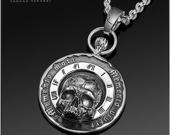 May include: Silver pocket watch pendant featuring a skull design and Roman numeral clock face. The watch face reads "Memento Mori" and "Memento Vivere".