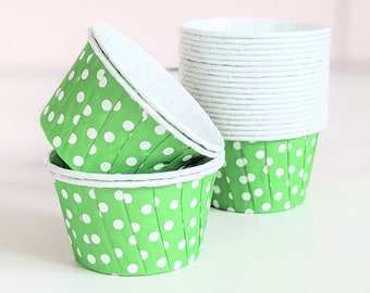 May include: Green cupcake cases with white polka dots. The cases are stacked and ready to use for baking.