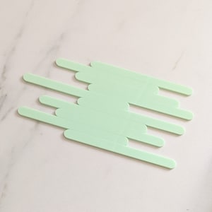 May include: A set of ten light green popsicle sticks arranged in a staggered pattern.