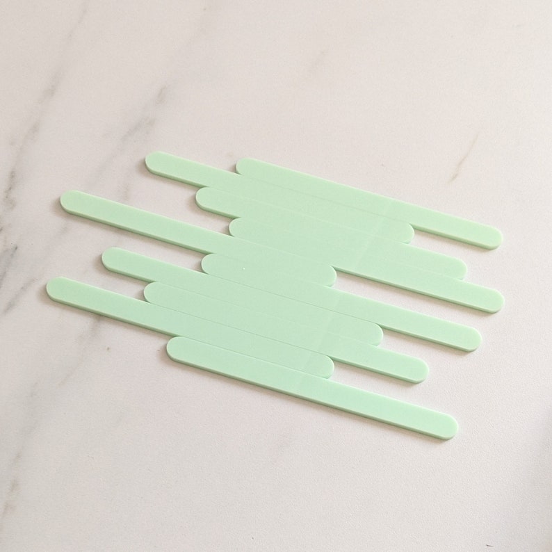 May include: A set of ten light green popsicle sticks arranged in a staggered pattern.
