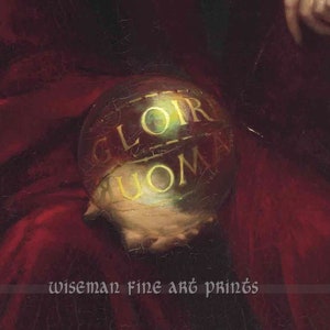 May include: A close-up of a gold-coloured sphere with the words "GLOIR" and "UOMA" inscribed on it. The sphere is resting on a red surface.