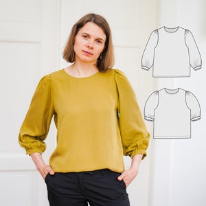 May include: A woman wearing a mustard yellow blouse with puffed sleeves and black pants. The image also includes a line drawing of a blouse with puffed sleeves.