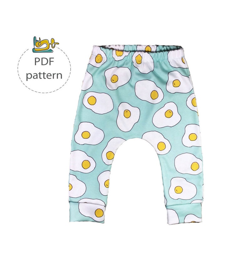 May include: PDF pattern for a pair of turquoise blue baby leggings with a white and yellow fried egg print.