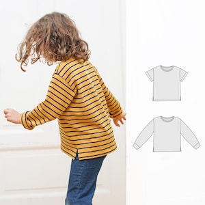 May include: A child wearing a yellow and navy striped long-sleeved shirt with side slits. Two line drawings of shirts are shown on a white background.