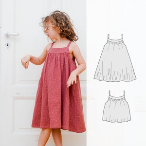 Könnte beinhalten: Ein junges Mädchen trägt ein rosa ärmelloses Kleid mit weißen Punkten. Das Kleid hat einen gerafften Rock und ein schlichtes Oberteil. Das Kleid wird neben einer Strichzeichnung eines ähnlichen Kleides gezeigt.