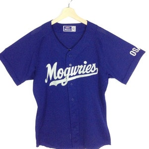 May include: A royal blue baseball jersey with white mesh fabric. The jersey has a white "Moguries" logo on the front and a white "OSA" logo on the right sleeve. The jersey has a button-up front.