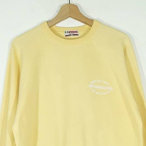 May include: A yellow sweatshirt with a white embroidered logo that says "Where you want to go, we'll take you there. McGregor"