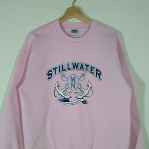 Puede incluir: Sudadera rosa con un gr&aacute;fico azul y blanco de dos anclas y el texto "STILLWATER MN EST. 1854 Tradition & Quality".