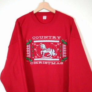 May include: Red sweatshirt with a festive design featuring a white rocking horse and the text "COUNTRY CHRISTMAS".