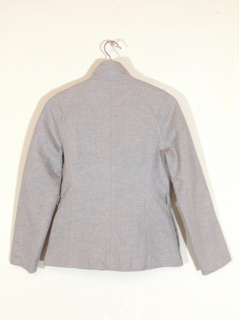 May include: A grey blazer with a stand-up collar and long sleeves.