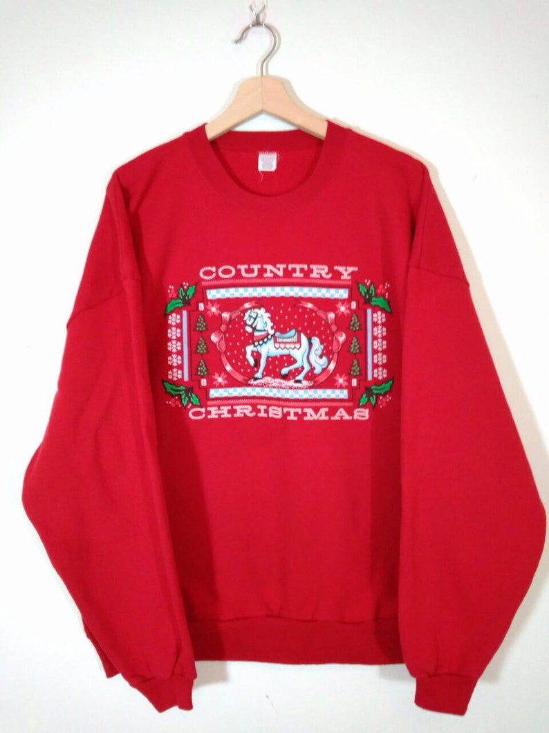 May include: Red sweatshirt with a festive design featuring a white rocking horse and the text "COUNTRY CHRISTMAS".