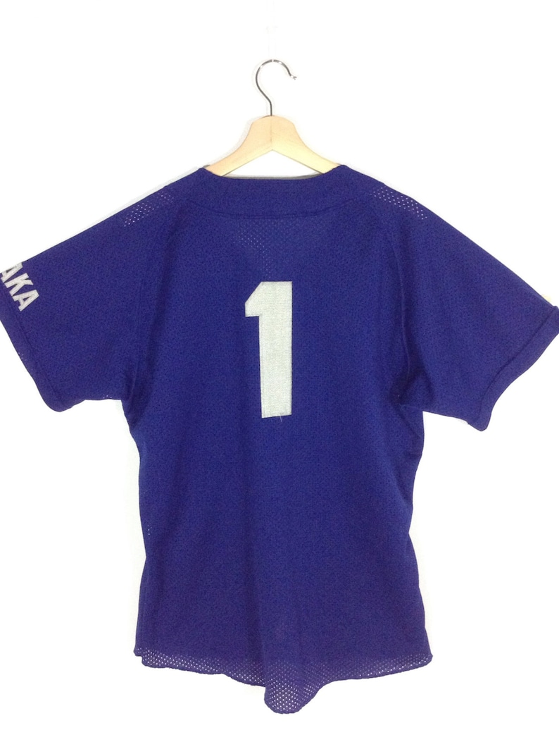 May include: A royal blue baseball jersey with a white number "1" on the back. The jersey has short sleeves and a mesh fabric.