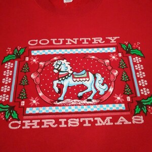 May include: Red sweatshirt with a white graphic design of a rocking horse and the text "COUNTRY CHRISTMAS".
