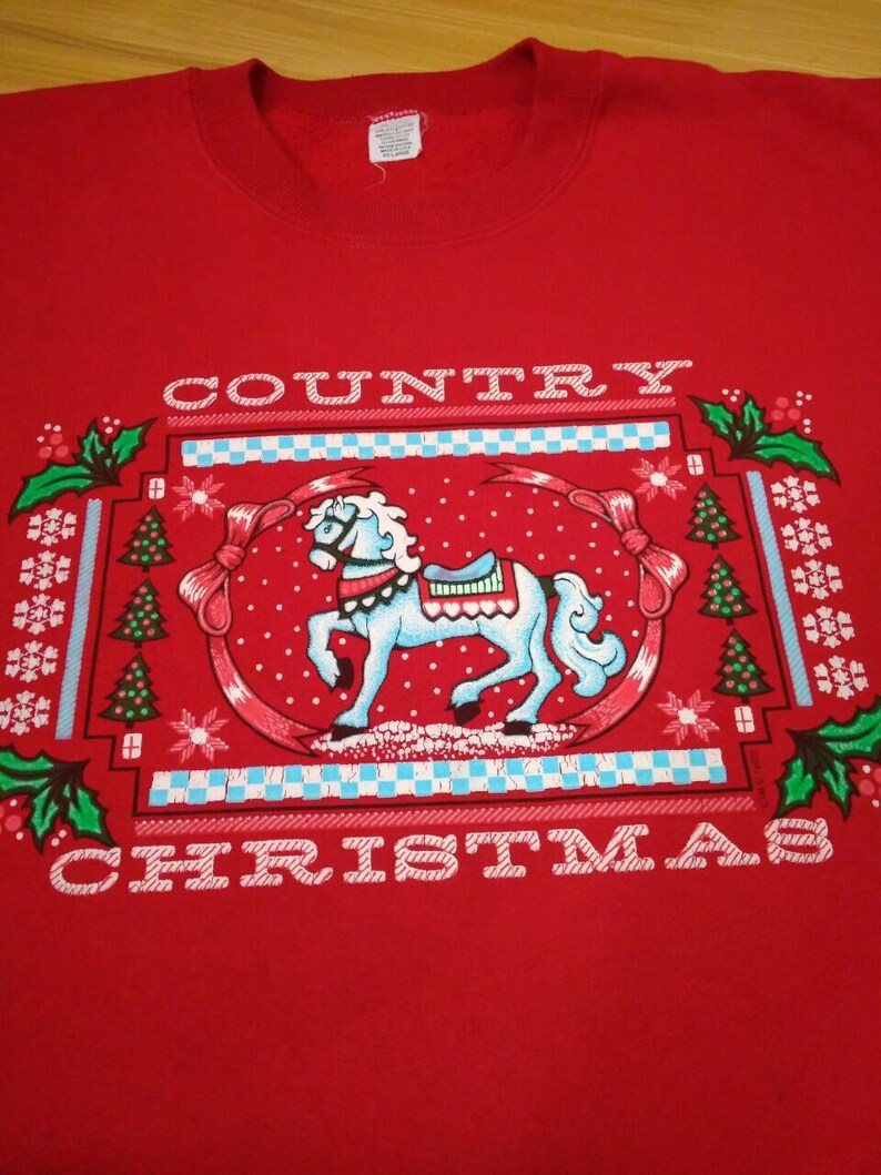 May include: Red sweatshirt with a white graphic design of a rocking horse and the text "COUNTRY CHRISTMAS".