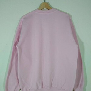 Puede incluir: Una sudadera rosa lisa con mangas largas y cuello redondo.