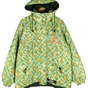 May include: A green and yellow patterned hooded jacket with a zipper and button closure. The jacket has a logo that says "Images of Nature" on the front. The jacket is made by the brand "Winder".